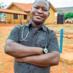 Dr. Boniface Batazari from Kigadye Health Center (Kigoma, Tanzania) in his workplace, showcasing the positive impact of improved healthcare services brought by the WASH facilities.