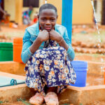 School girl sitting in front of tap stand.