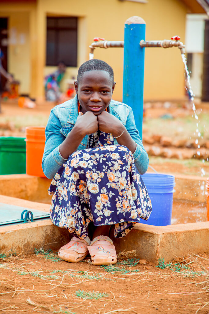 School girl sitting in front of tap stand.