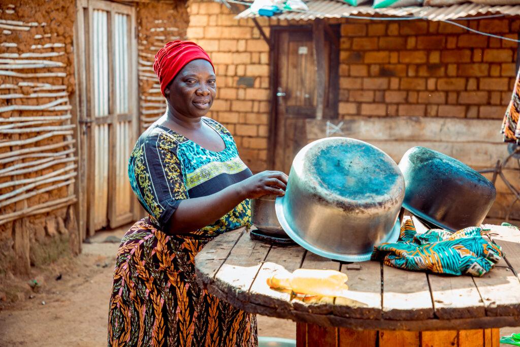 Janeth a resident of Kigadye village in Kigoma, Tanzania using clean and safe water provided by WASH facilities to wash her household dishes.