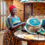 Janeth a resident of Kigadye village in Kigoma, Tanzania using clean and safe water provided by WASH facilities to wash her household dishes.