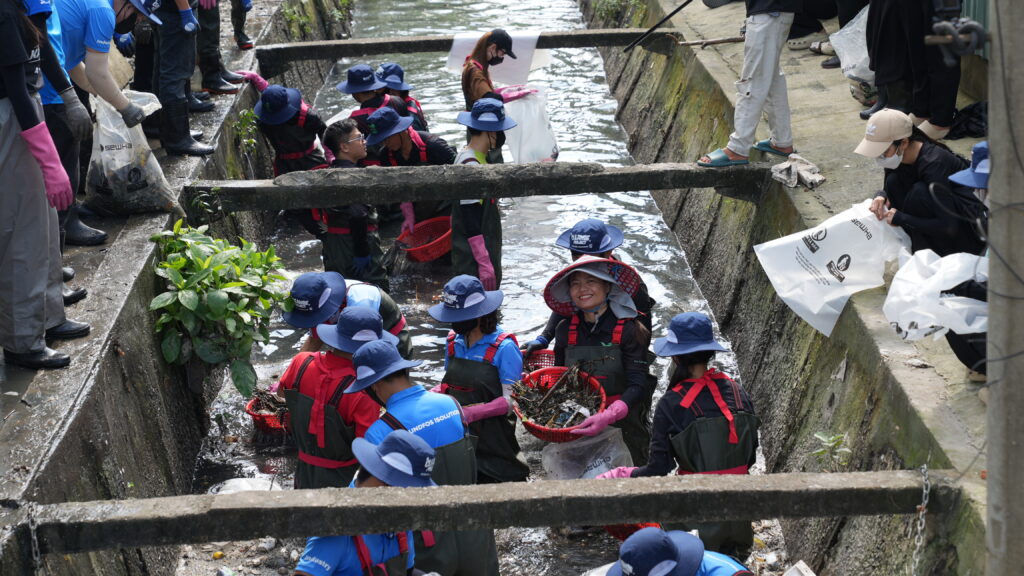 Volunteers collectinng garbage from water.