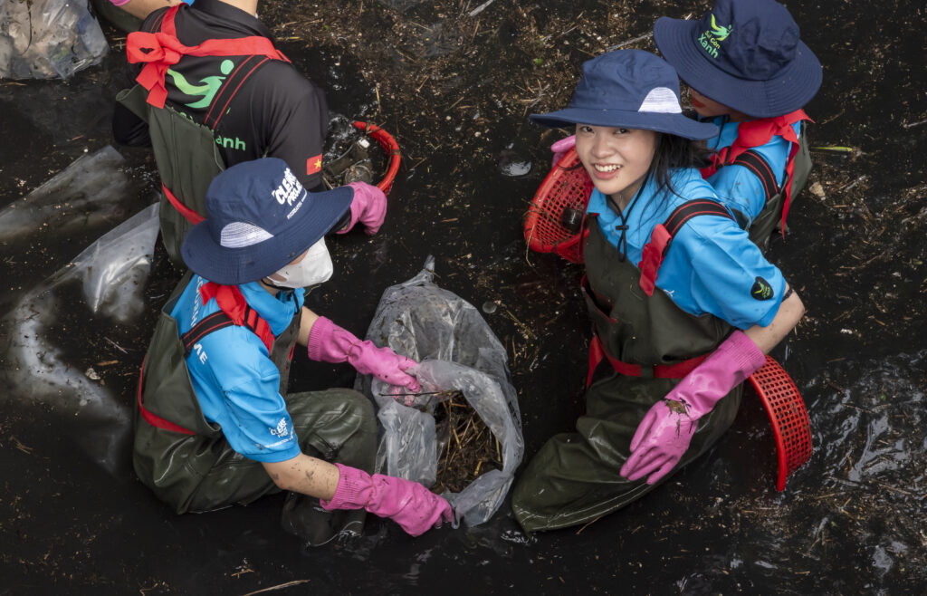 Volunteers collectinng garbage from water.