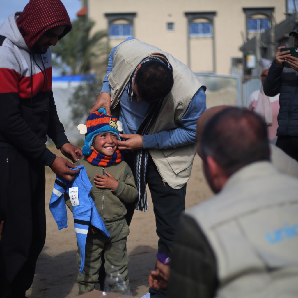 UNICEF staff delivering fresh warm clothes to Palestinian boy in Gaza 